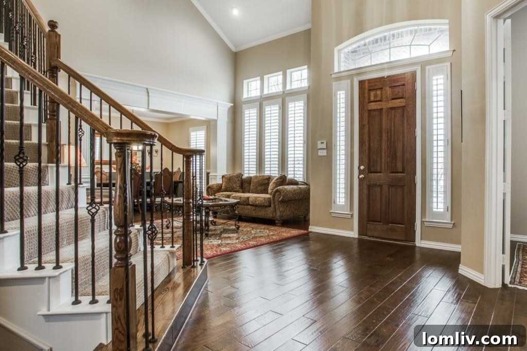 A grand foyer with a wrought iron staircase, hardwood floors, and abundant natural light, showcasing the home's elegant entrance.