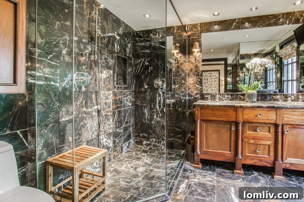 The master bathroom featuring a custom mahogany vanity with a marble slab countertop and modern fixtures.
