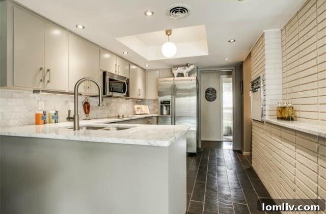 Modern kitchen with Carrera marble counters, brick wall, and stainless steel appliances
