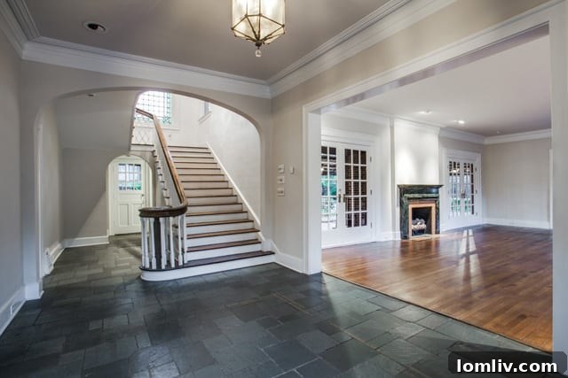 The stately foyer of Carrie Marcus Neiman's historic Dallas home featuring modern slate floors and a glass pendant light fixture