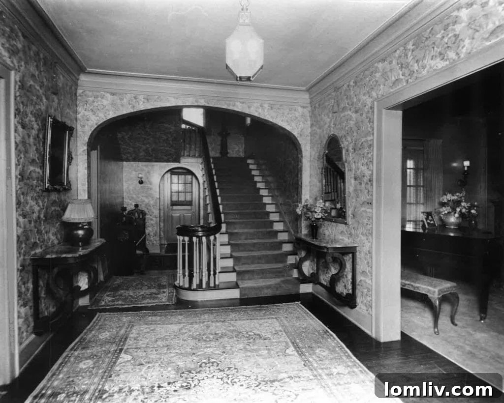 Archival photo of the Carrie Marcus House foyer, showing original toile wallpaper, hardwood floors, and a vintage lantern-style pendant