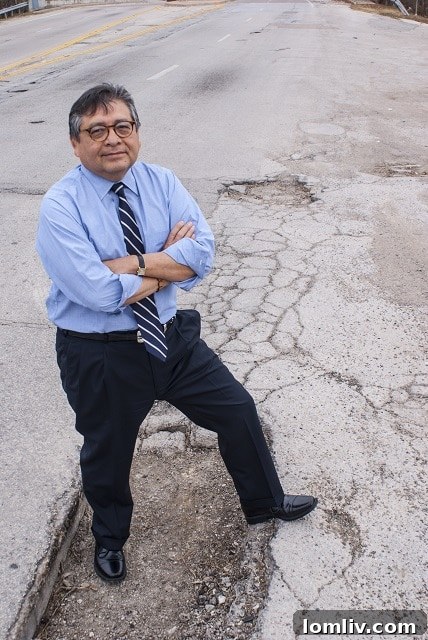 Man pointing at a large pothole in Dallas road
