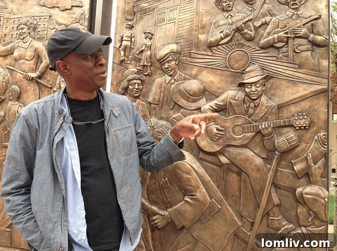 Blues musician Keb Mo gesturing to Robert Johnson in the 'The Birth of a City' bronze sculpture wall at Encore Park.