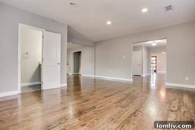 The beautifully renovated living space, featuring new hardwood floors, ample natural light, and modern recessed lighting.