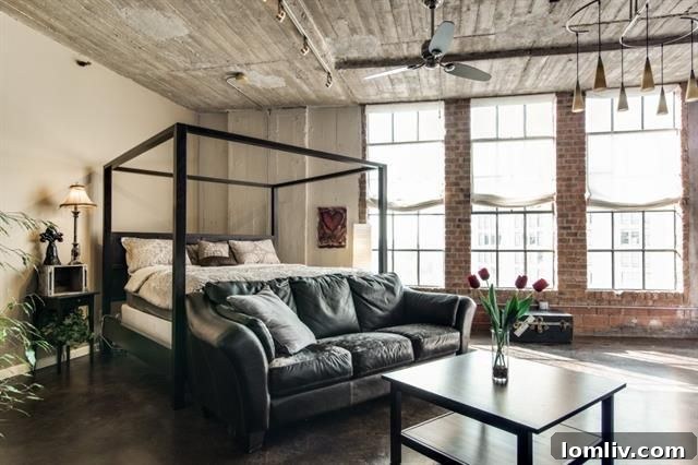 Master sleeping area set near large windows in the loft, showing polished concrete floors