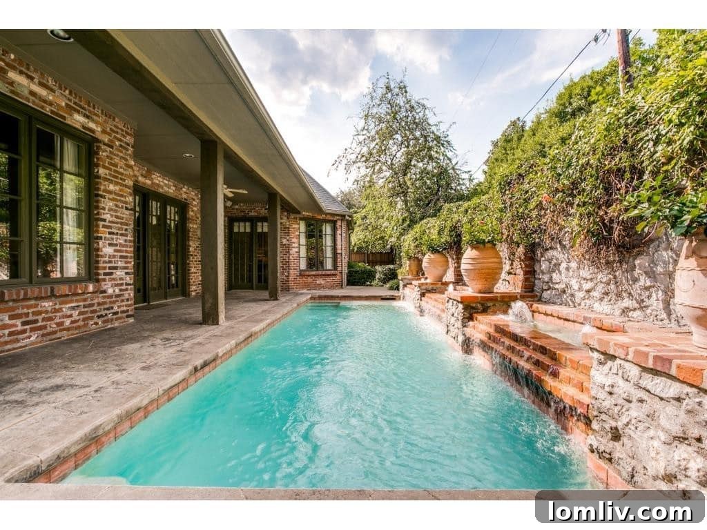 Elegant lap pool with a waterfall feature, surrounded by mature landscaping