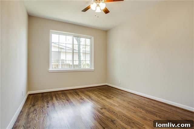 One of the three bedrooms, showcasing refinished hardwoods, a ceiling fan, and new windows.
