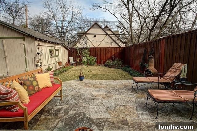 Lush backyard with a raised stone patio and mature landscaping