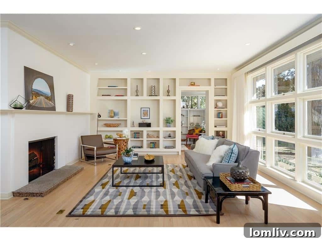 Bright living room with bleached white oak floors, a wall of built-in bookshelves, and a modern fireplace, offering natural light