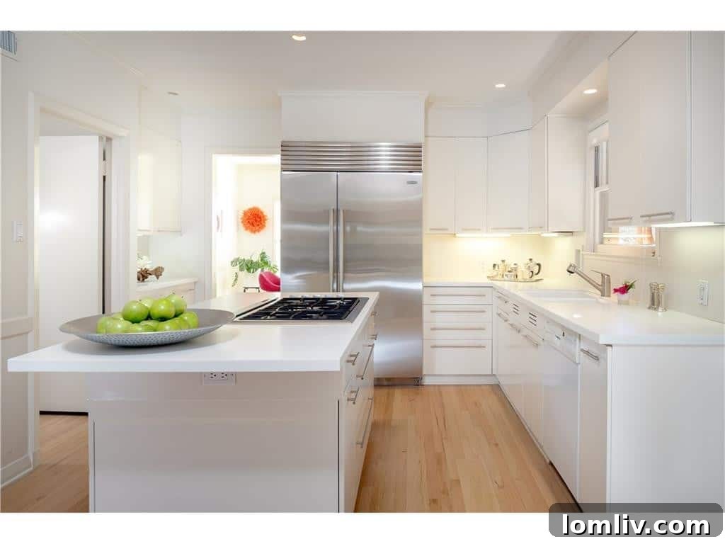 Modern all-white kitchen with stainless steel appliances, a central island with gas range, and minimalist design