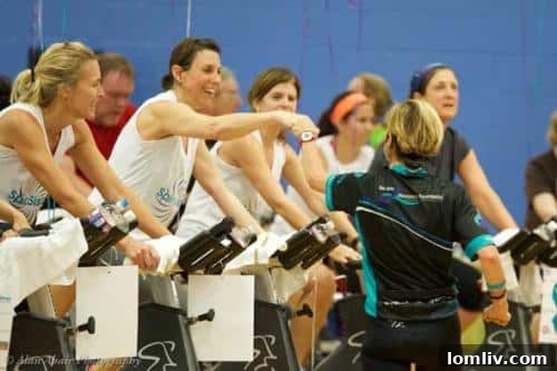 Group of participants enthusiastically cycling during a Wheel to Survive fundraiser event.
