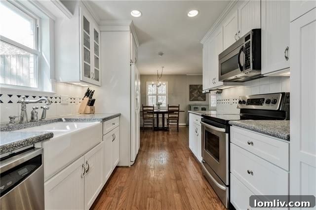 Modern galley kitchen with white cabinets and stainless steel appliances