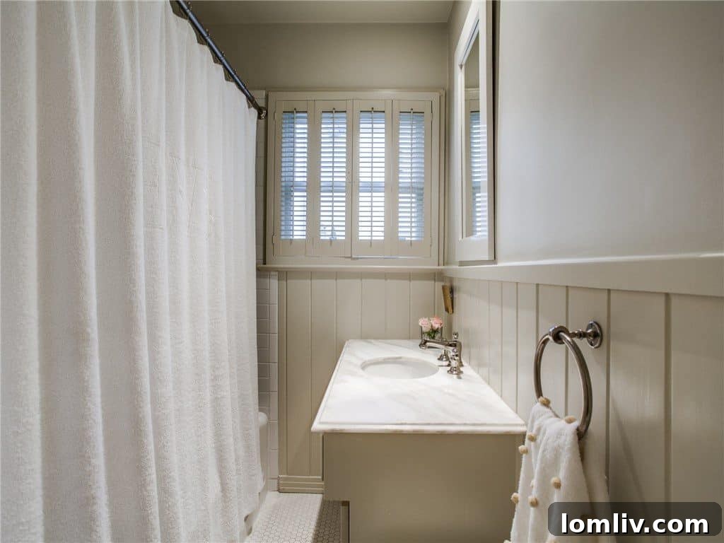 Beautifully updated bathroom with penny-round tile, wainscoting, and marble vanity
