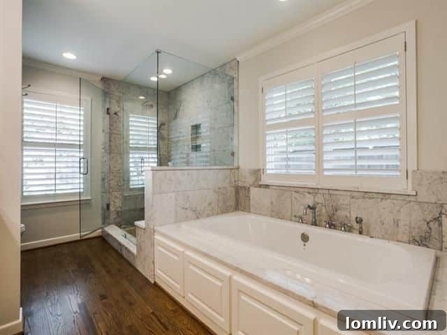 Luxurious master bathroom featuring marble accents, a soaker tub, and frameless glass shower