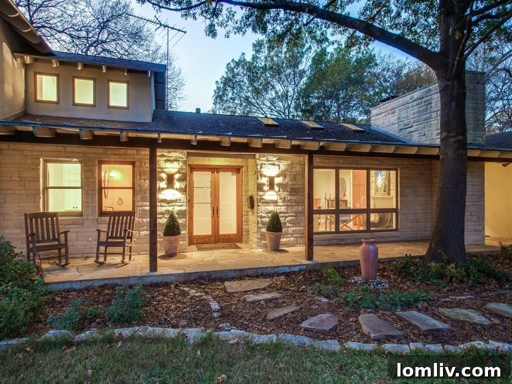 Frank Welch Protégé Redefines Texas Contemporary in Lake Park Estates 3 Inviting front entrance of the remodeled home, featuring a covered stone porch and architectural details hinting at modern vernacular style.