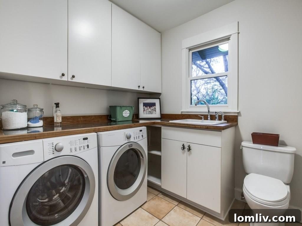Frank Welch Protégé Redefines Texas Contemporary in Lake Park Estates 22 Efficient and stylish laundry room featuring stainless steel countertops, wood trim, and a convenient spare toilet for added functionality.