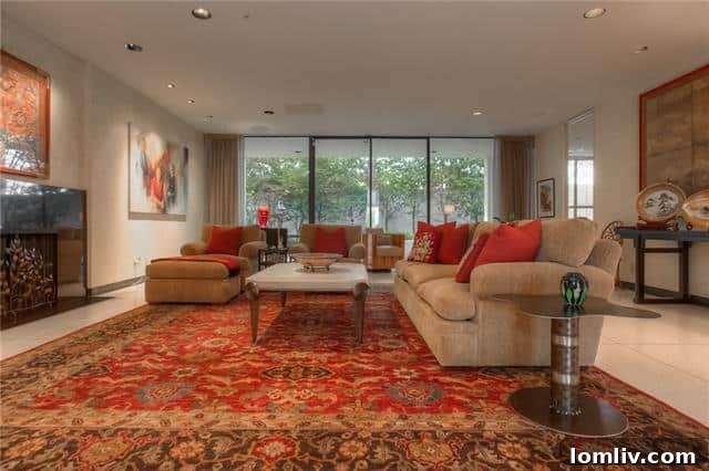 Spacious living room with a large gas fireplace and floor-to-ceiling glass doors opening to a private garden.