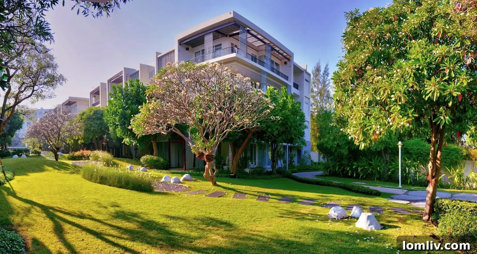 A modern apartment building with lush green trees in the foreground, showcasing a blend of urban living and nature.